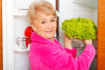senior woman getting vegetable in the refrigerator